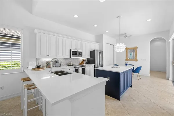 a kitchen with stainless steel appliances kitchen island granite countertop a sink a stove and a refrigerator