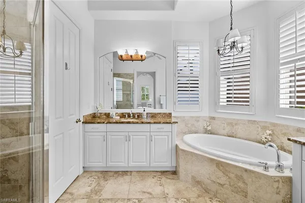 a spacious bathroom with a tub a sink and mirror