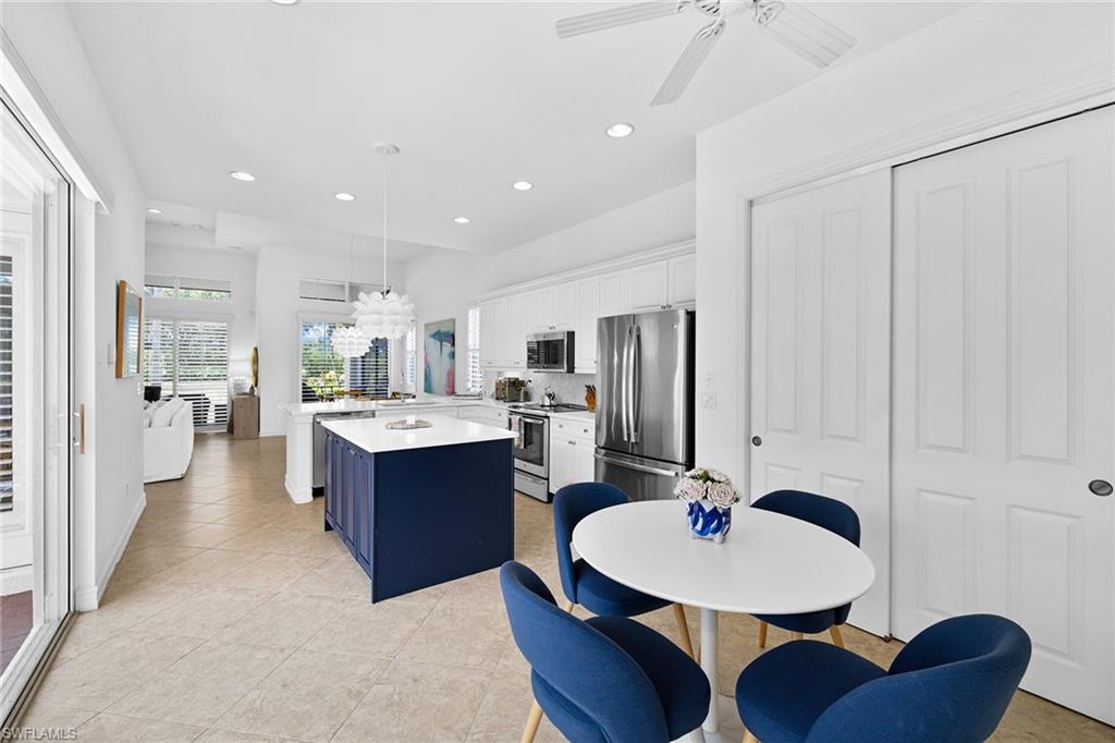 7785 Ashton Road Naples, FL 34113 - Photo 8 of 39 a kitchen with stainless steel appliances kitchen island granite countertop a sink a refrigerator and chairs