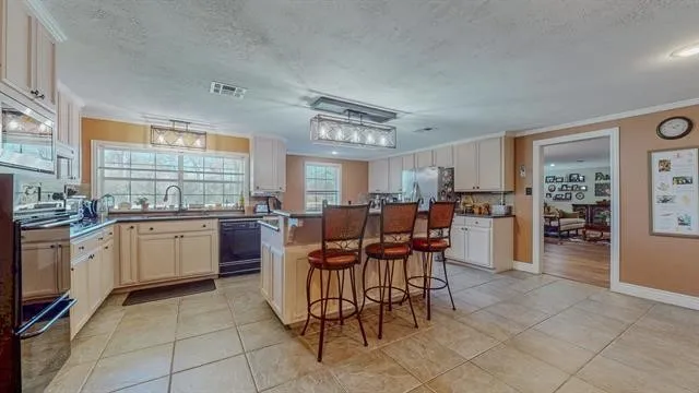 a kitchen with stainless steel appliances kitchen island granite countertop a table chairs and a refrigerator