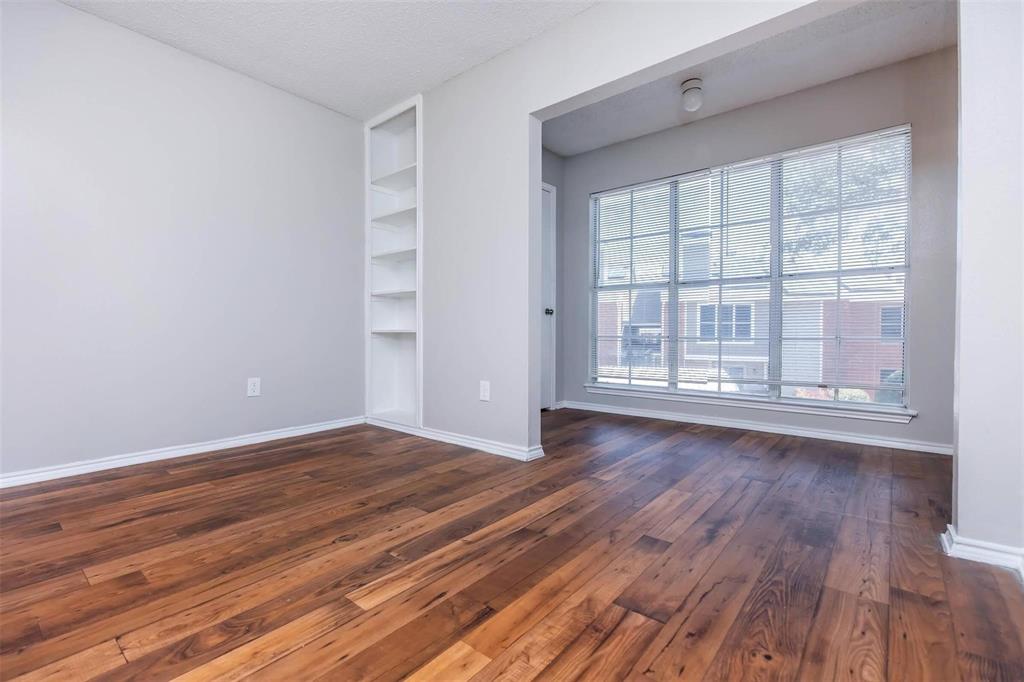 1826 Esters Road, Unit 1050 Irving, TX 75061 - Photo 19 of 39 Wood-finish flooring, built-in shelving, white trim, and a large window with horizontal blinds