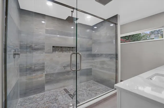 a bathroom with a shower and a sink a mirror