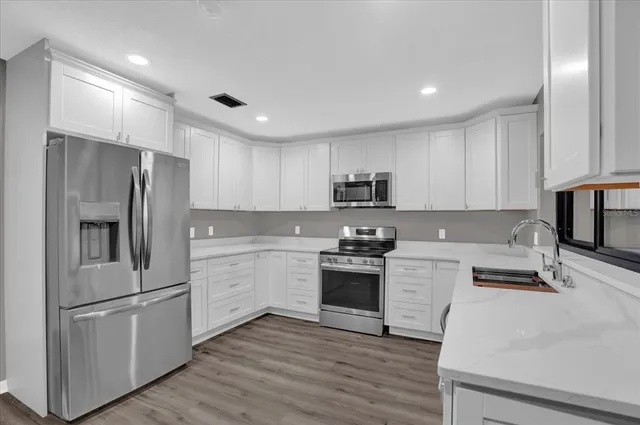 a kitchen with stainless steel appliances granite countertop a refrigerator stove microwave and sink