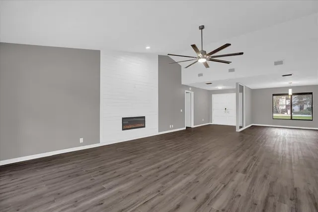 a view of an empty room with window and wooden floor