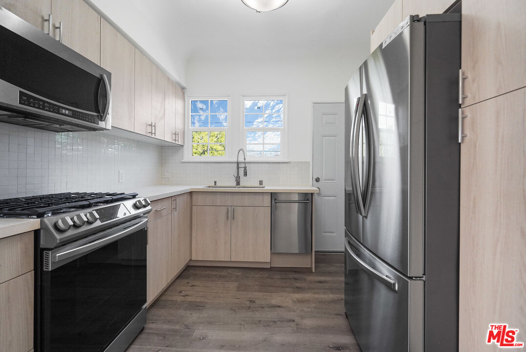 228 South Reeves Drive, Unit D Beverly Hills, CA 90212 - Photo 5 of 13 a kitchen with stainless steel appliances granite countertop a refrigerator stove and microwave