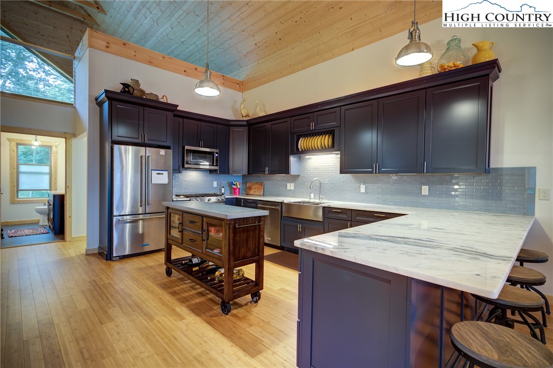 111 Boca Ridge Road Boone, NC 28607 - Photo 10 of 44 a kitchen with stainless steel appliances granite countertop a refrigerator a sink dishwasher a stove a dining table and chairs with wooden floor