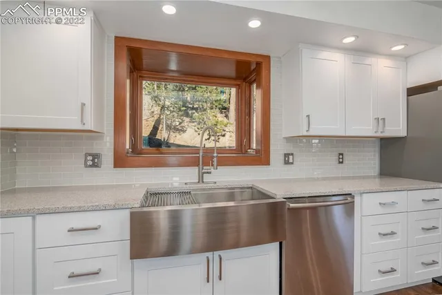 a kitchen with granite countertop white cabinets and window