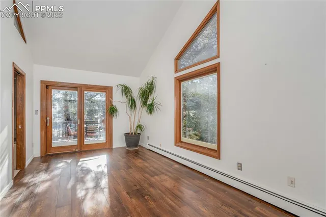 an empty room with wooden floor fan and windows
