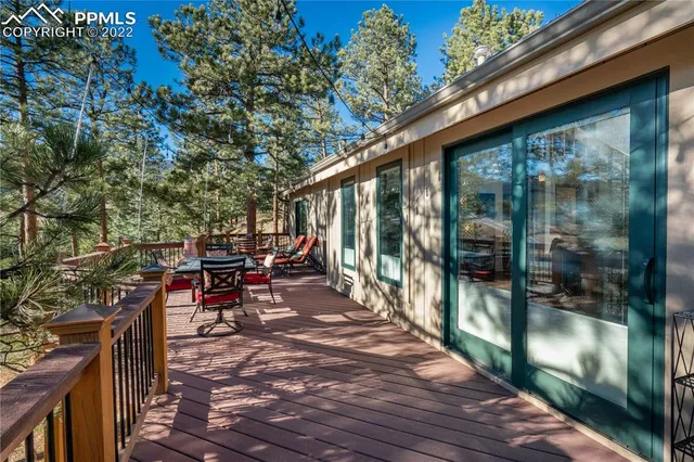 a view of a patio with table and chairs and floor to ceiling window wooden floor and fence