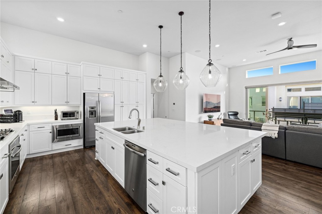 134 Stellar Irvine, CA 92618 - Photo 2 of 49 a large white kitchen with stainless steel appliances granite countertop a stove a sink a refrigerator and white cabinets with wooden floor