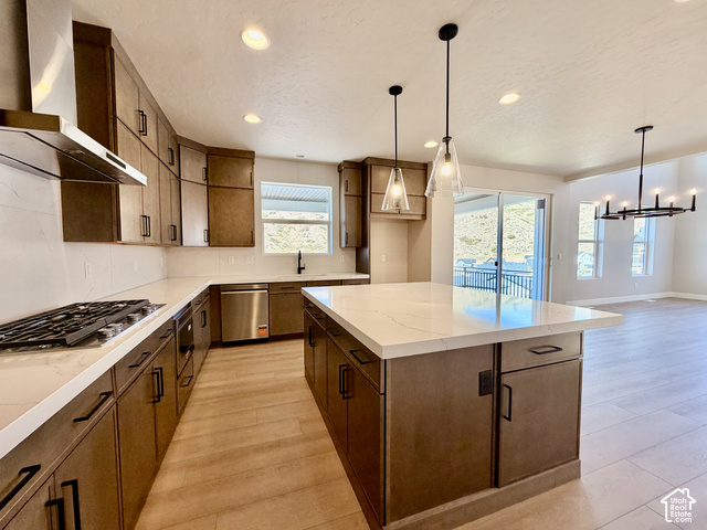 1595 West Canyon Rim Road, Unit 630 Lehi, UT 84048 - Photo 9 of 41 Spacious kitchen featuring an expansive island with a white countertop, wood-finish cabinetry with black hardware, wood-finish flooring, and a stainless steel gas range with a matching range hood