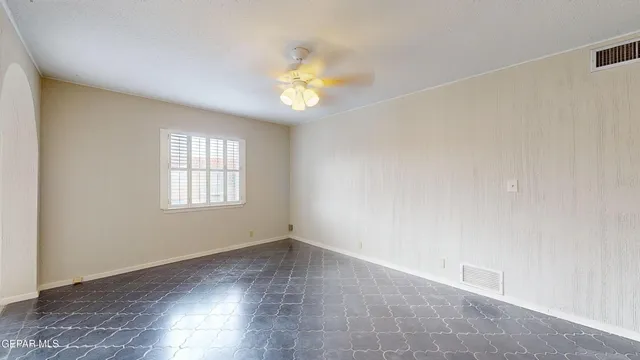 an empty room with a window and a fan