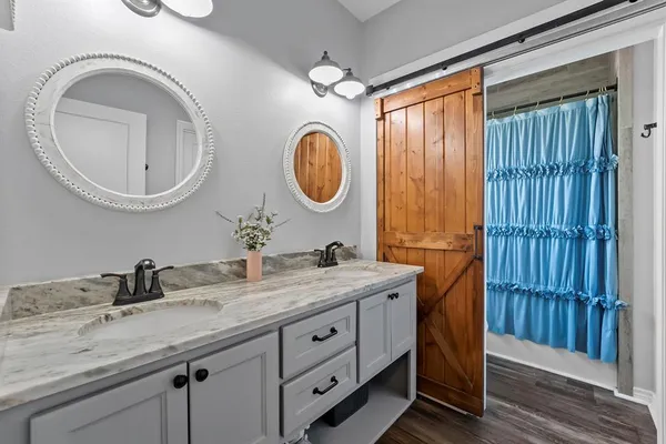 a bathroom with a granite countertop double vanity sink a mirror and a window