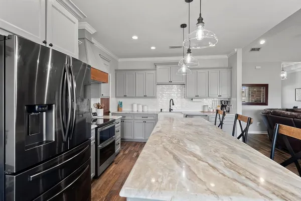 a large kitchen with kitchen island a large counter top space a sink stainless steel appliances and cabinets