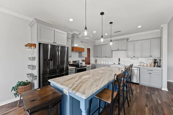 a kitchen with kitchen island a refrigerator a stove a dining table and chairs