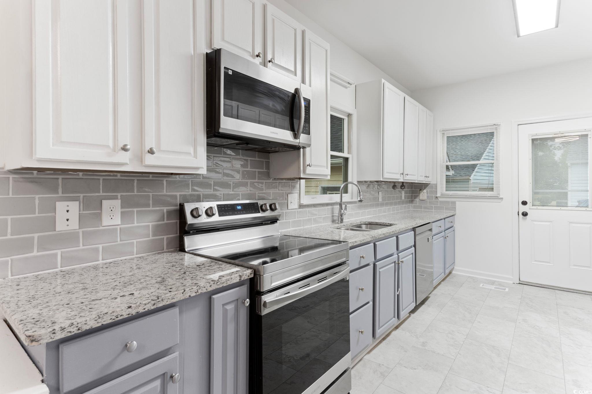 2321 Brick Drive Longs, SC 29568 - Photo 17 of 40 Kitchen with stainless steel appliances, decorative backsplash, white cabinetry, and light stone counters