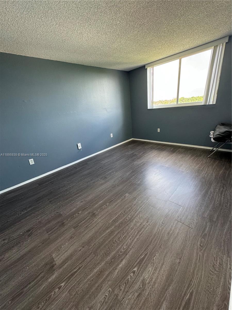 1251 Northeast 108th Street, Unit 602 Miami, FL 33161 - Photo 9 of 11 an empty room with wooden floor and windows