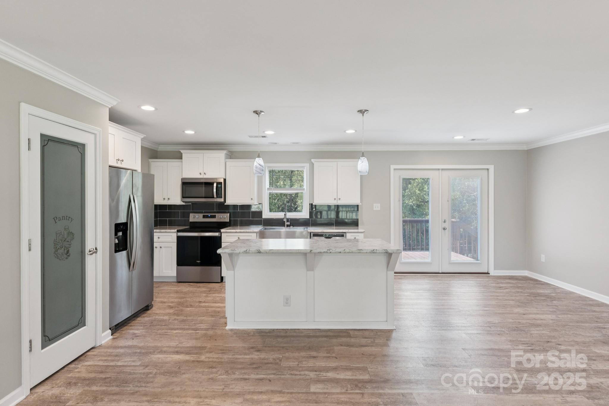 1259 Hardin Road Dallas, NC 28034 - Photo 5 of 16 a kitchen with stainless steel appliances kitchen island granite countertop a stove top oven a refrigerator a sink a microwave oven with white cabinets and wooden floor