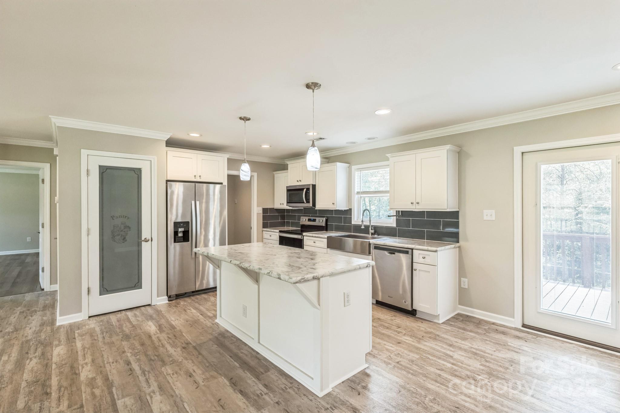 1259 Hardin Road Dallas, NC 28034 - Photo 6 of 16 a large kitchen with kitchen island a sink dishwasher a refrigerator and white cabinets with wooden floor