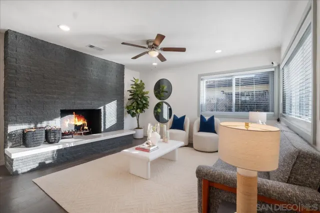 a living room with furniture a fireplace and a large window