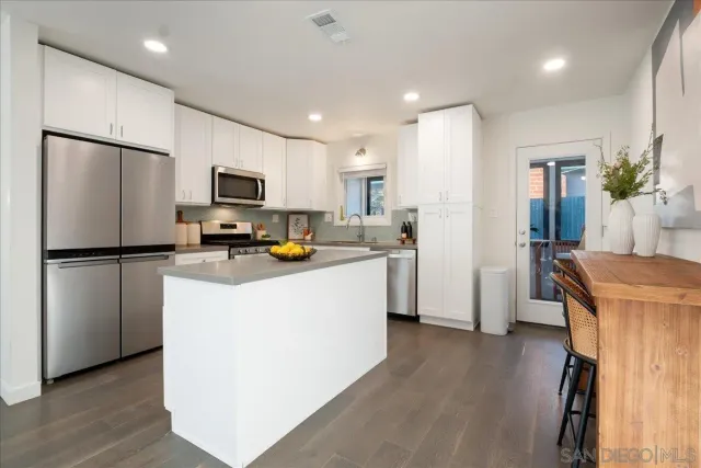 a kitchen with a refrigerator a stove top oven a counter space and wooden floor