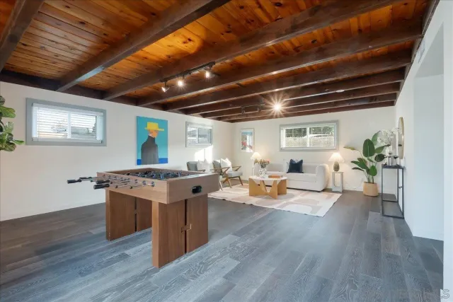 a living room with stainless steel appliances granite countertop couches wooden floor and a table