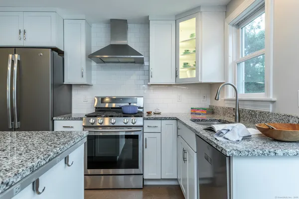 a kitchen with granite countertop a sink stove and refrigerator