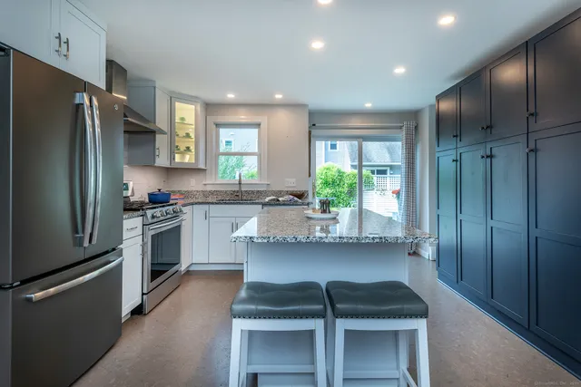 a kitchen with kitchen island white cabinets and stainless steel appliances