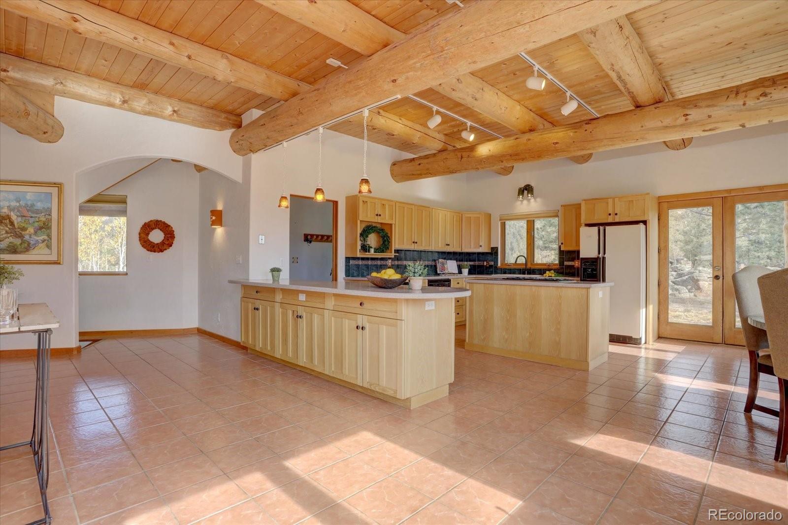 12227 Calfee Gulch Road Conifer, CO 80433 - Photo 14 of 43 a kitchen with stainless steel appliances kitchen island granite countertop a refrigerator and wooden cabinets