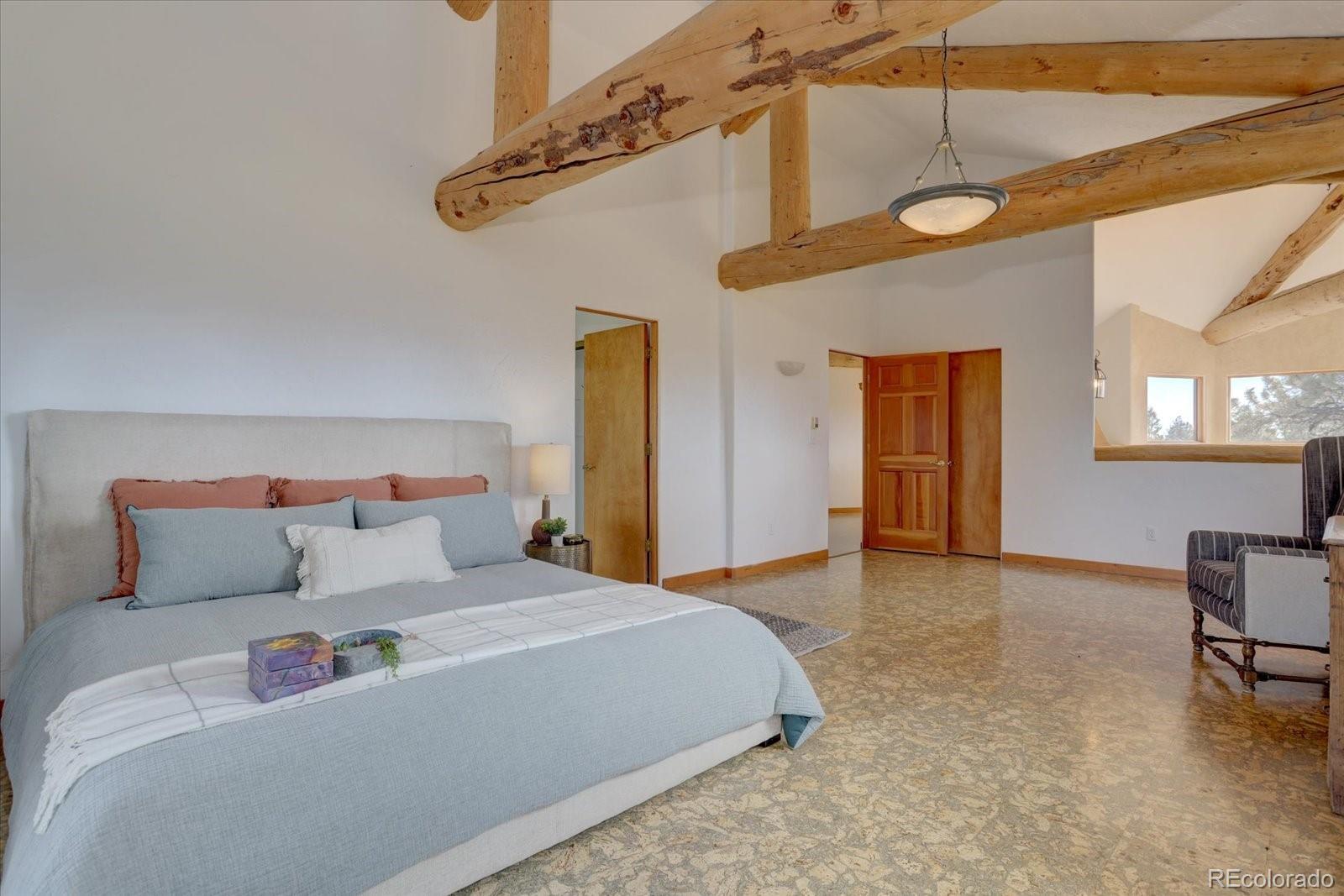 12227 Calfee Gulch Road Conifer, CO 80433 - Photo 22 of 43 a bedroom with a bed a table and chair