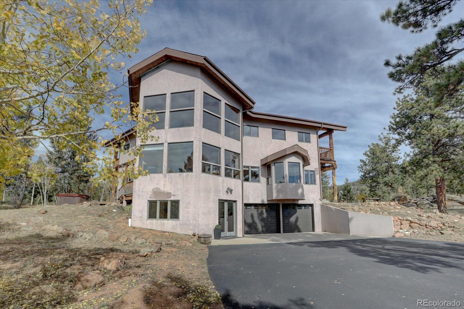 12227 Calfee Gulch Road Conifer, CO 80433 - Photo 4 of 43 a front view of a house with large windows
