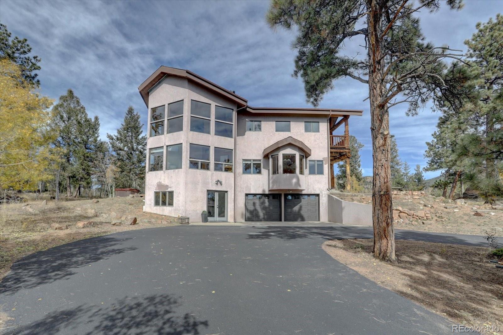 12227 Calfee Gulch Road Conifer, CO 80433 - Photo 5 of 43 a view of a white house with large tree and wooden fence