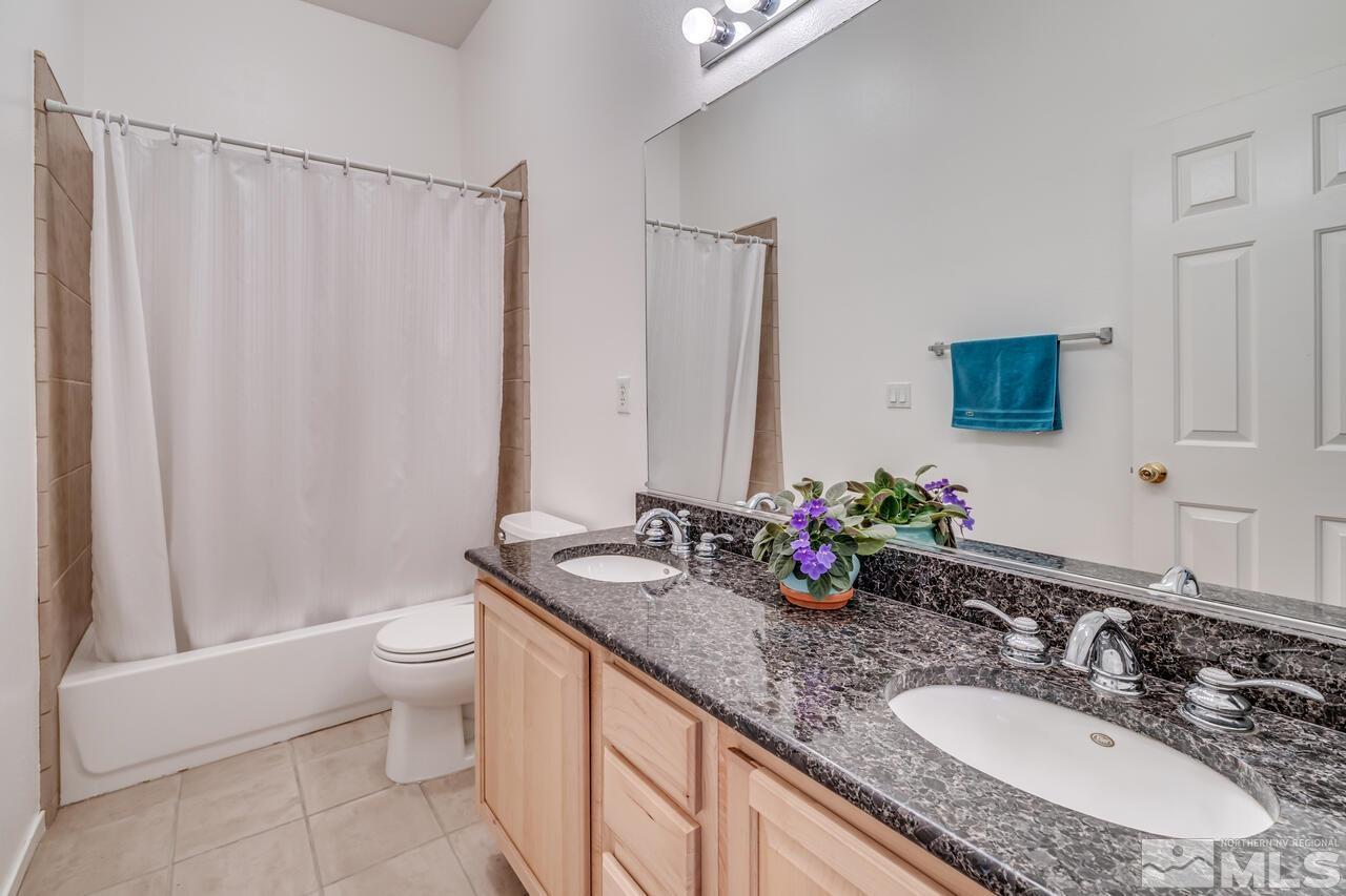 10645 Blue Moon Court Reno, NV 89521 - Photo 23 of 33 a bathroom with double vanity sinks a toilet a mirror and shower