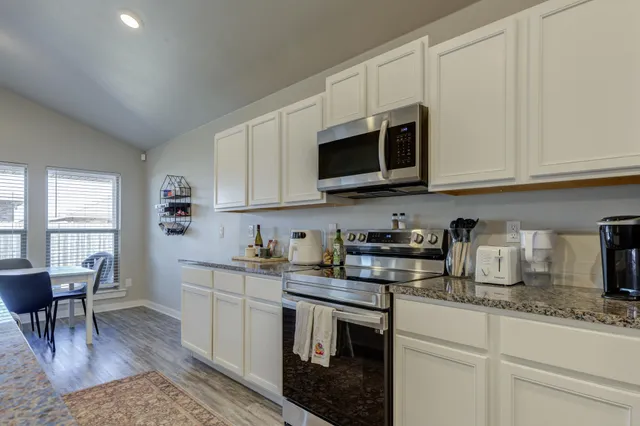 a kitchen with stainless steel appliances granite countertop a stove a sink a microwave and cabinets