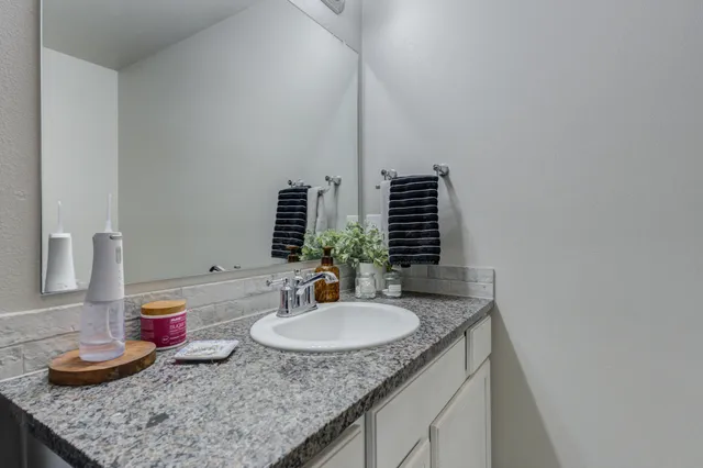 a bathroom with a granite countertop sink and a mirror