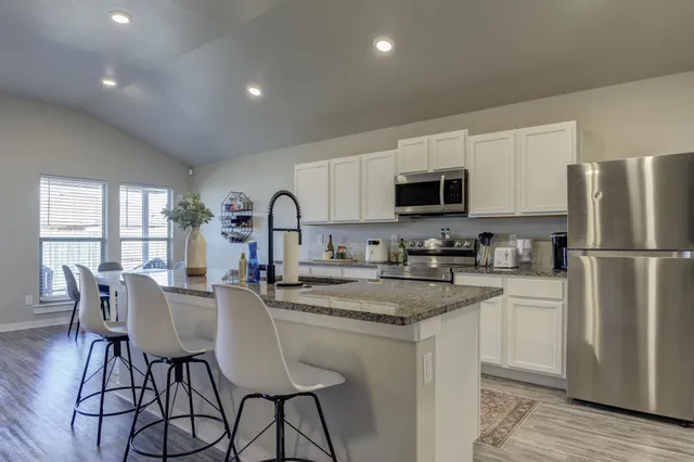 a kitchen with refrigerator a stove a sink and chairs