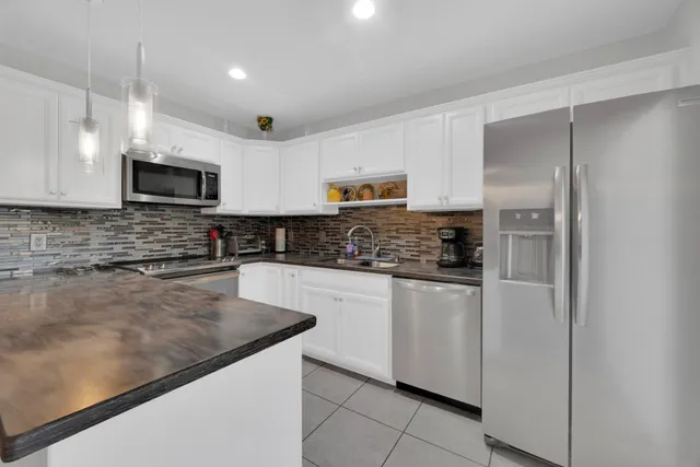 a kitchen with stainless steel appliances granite countertop a refrigerator a stove a sink and a microwave