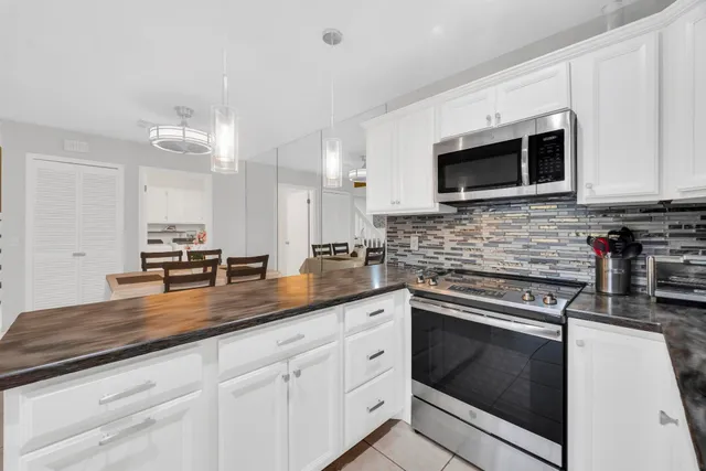 a kitchen with stainless steel appliances granite countertop grey cabinets a stove a sink and a microwave