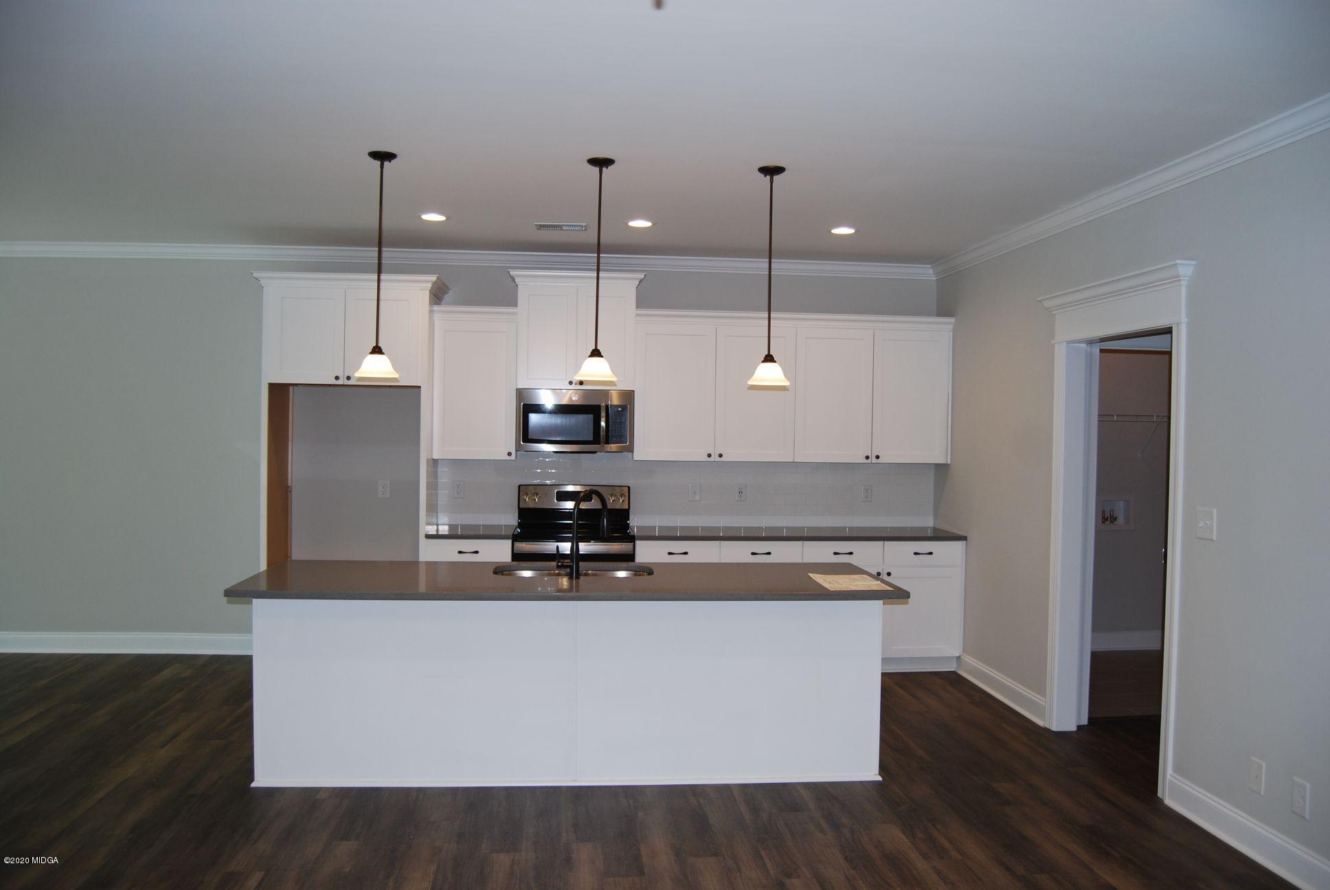 65 Carters Way Forsyth, GA 31029 - Photo 5 of 13 a kitchen with kitchen island stainless steel appliances a sink a stove a refrigerator and white cabinets