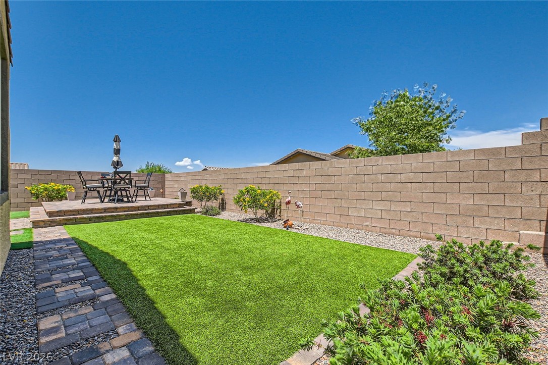 498 Pebble Run Avenue Henderson, NV 89011 - Photo 22 of 47 Relax in this tranquil backyard featuring a spacious patio and lush artificial turf.