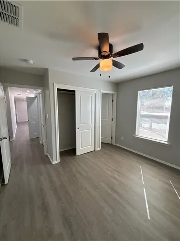 an empty room with windows and fan