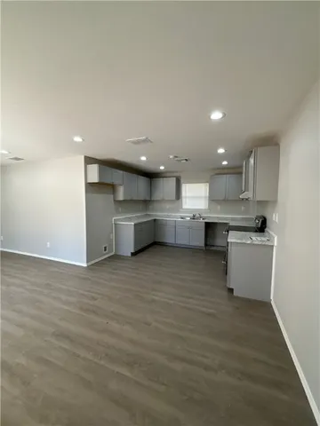 a large kitchen with a large counter top a sink stainless steel appliances and cabinets