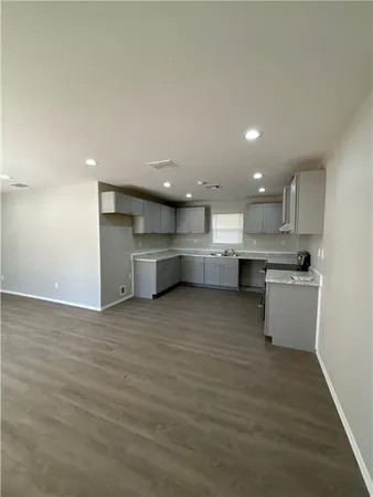 a large kitchen with a large counter top a sink stainless steel appliances and cabinets