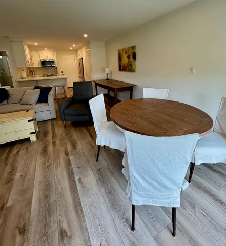 a living room with couches and kitchen view with wooden floor