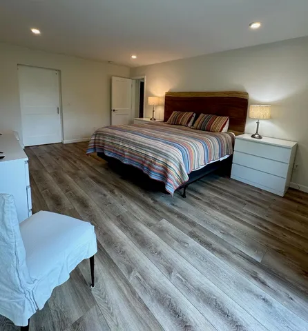 a bedroom with a bed a mirror and wooden floor