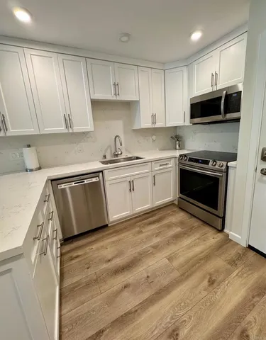 a kitchen with stainless steel appliances granite countertop a stove a sink and a microwave