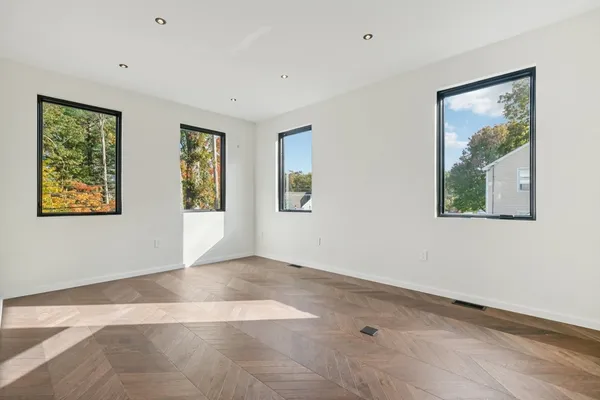 a view of an empty room with window and wooden floor