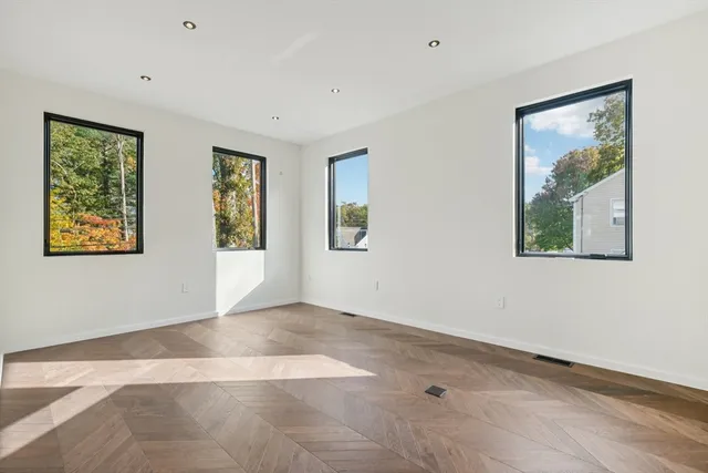 a view of an empty room with window and wooden floor