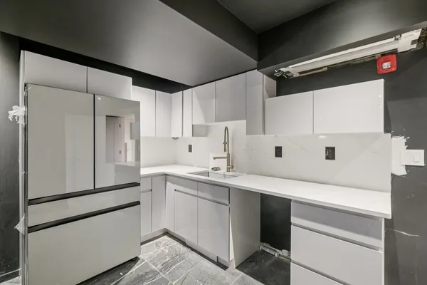 a kitchen with a sink a refrigerator and cabinets