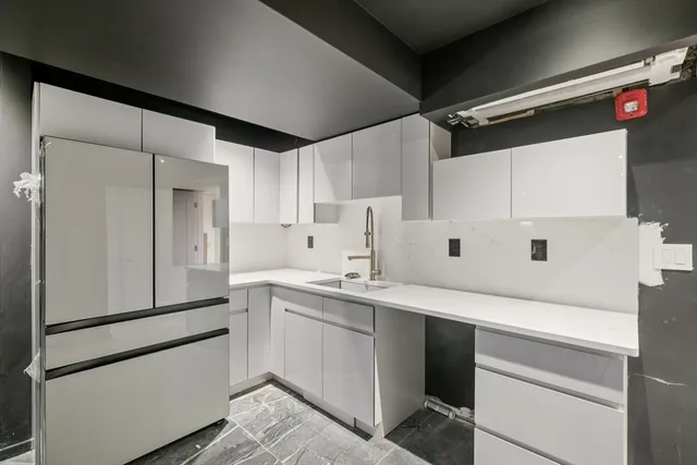a kitchen with a sink a refrigerator and cabinets